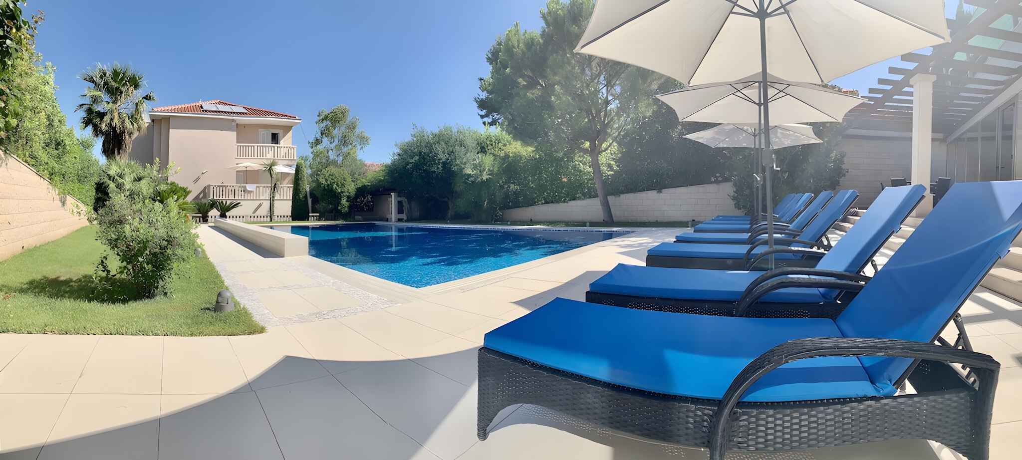 A swimming pool with blue lounge chairs and umbrellas.