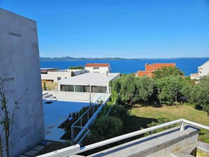 Un edificio moderno con piscina, vista al mar y cielo despejado.