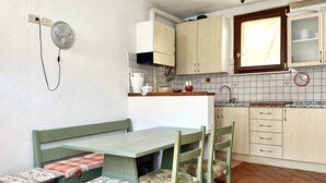 Una cucina con una panca e sedie, un orologio, pensili e una finestra.