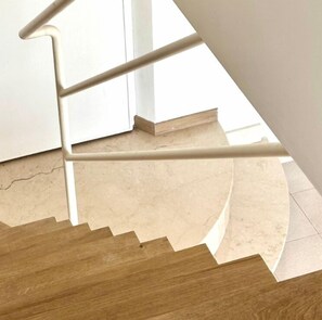 A staircase with a wooden handrail and beige steps.