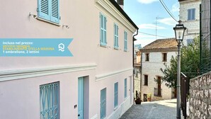 A narrow street with pastel-colored buildings, a stone wall, and a street lamp. - N254 - Numana, sky-earth with a wonderful garden overlooking the sea (Numana)