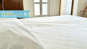 A room with a large bed, a wooden headboard, a window with blinds, and a door. - N254 - Numana, sky-earth with a wonderful garden overlooking the sea (Numana)