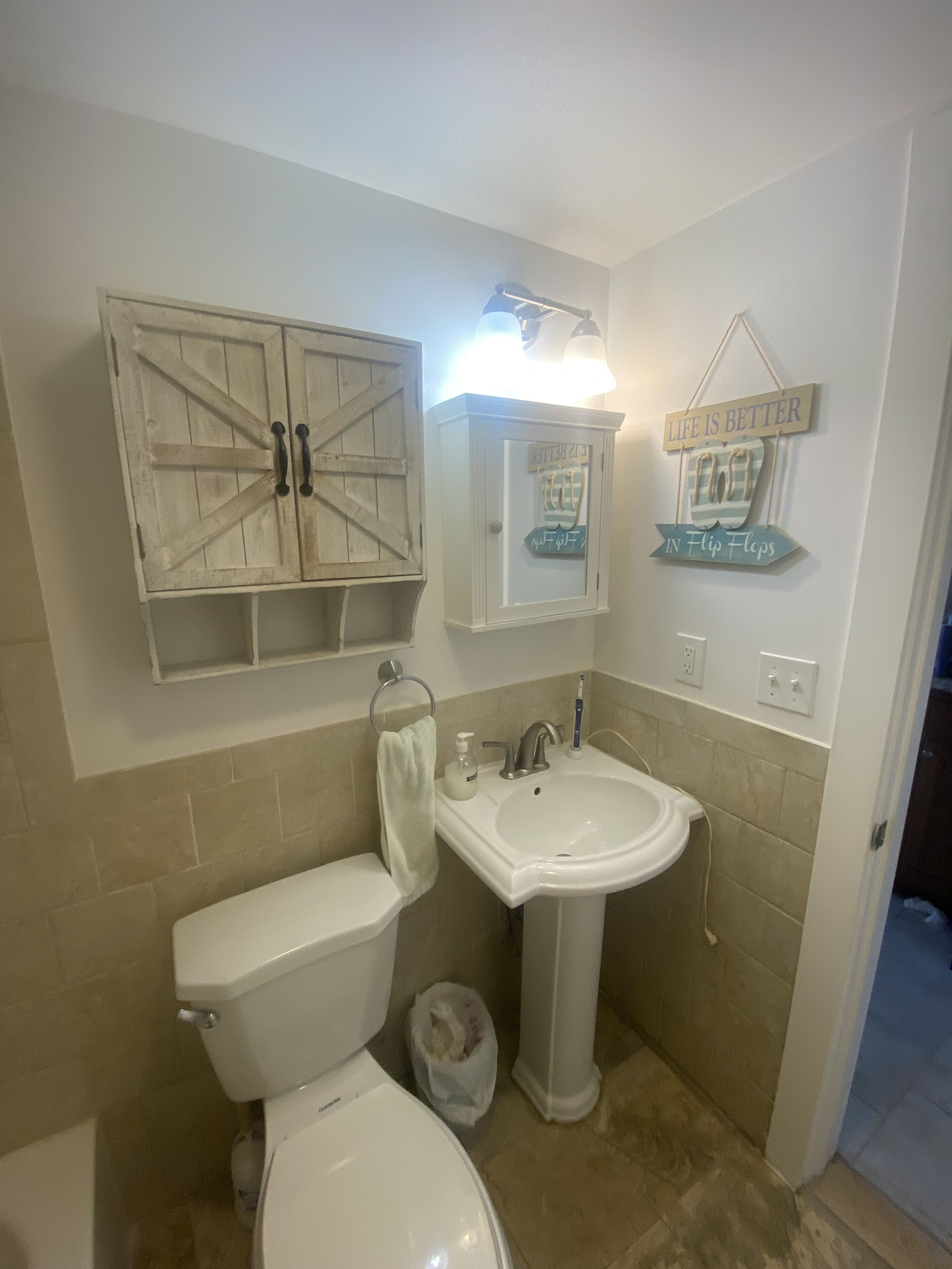 Un baño con inodoro, lavabo y un armario decorativo.