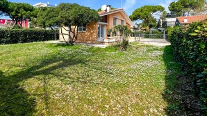 Une maison avec un toit en pente, une antenne parabolique et un petit jardin avec de la pelouse et des fleurs.