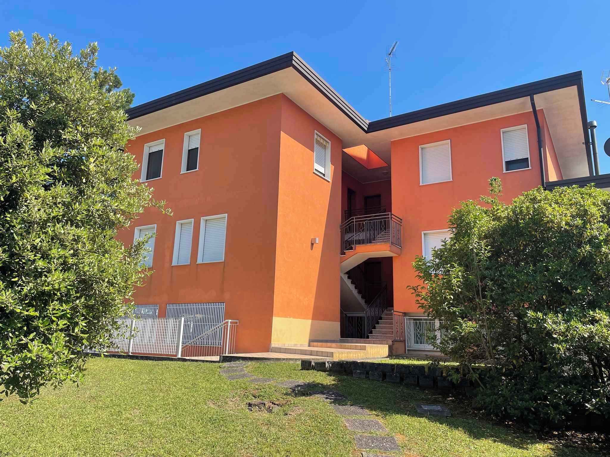 Un immeuble de deux étages avec une façade rouge, un balcon au deuxième étage et un escalier menant à l’étage supérieur.