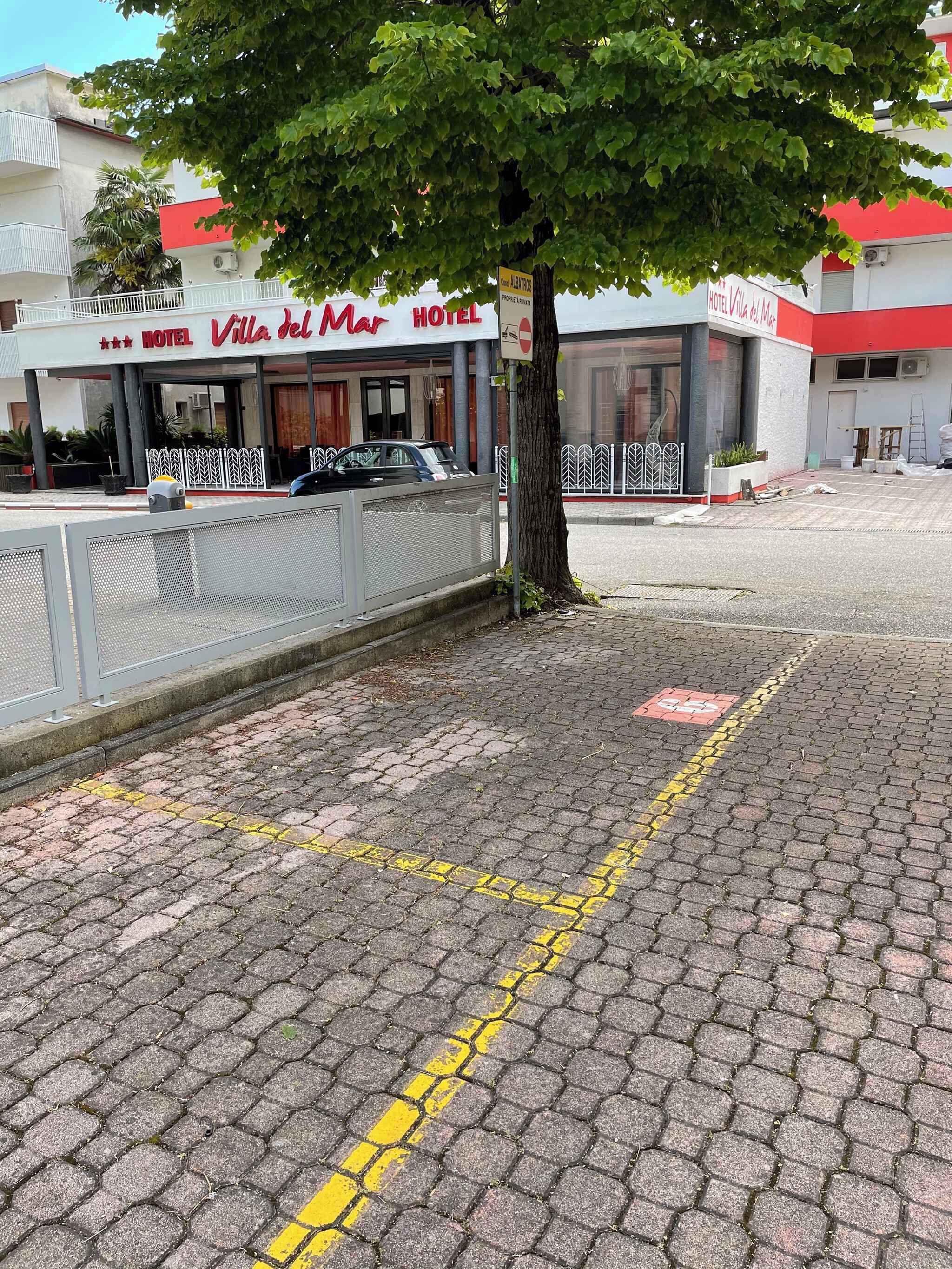 Un hôtel appelé «Villa del Mar», avec une entrée dallée et un arbre devant.