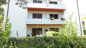 A multi-story building with balconies, a flat roof, and a well-maintained garden area. - Holiday apartment in a quiet and central location, completely renovated (Bibione)