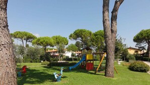 A playground with slides and swings surrounded by trees and buildings.