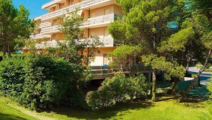 A multi-story hotel with balconies, surrounded by lush greenery and trees.