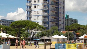 En byggnad med flera våningar och balkonger, troligen ett hotell eller ett bostadskomplex, med en sandstrand i förgrunden.