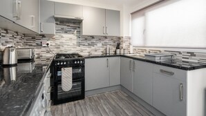 A modern kitchen with grey cabinets, a black stove, and a tiled backsplash.