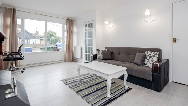 A modern living room with a white coffee table, grey sofa, and a striped rug.