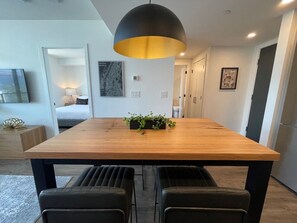 Un espace repas moderne avec une table en bois, des chaises noires et un luminaire suspendu noir.