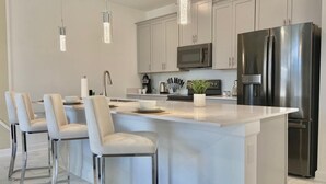 A modern kitchen with a central island, stainless steel appliances, and pendant lighting. - Beautiful 4BD/3BA Townhome with Pool 280 (Kissimmee)