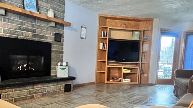 A living room with a fireplace, a television, and a bookshelf. - Large Private Condo on the Golf Course close to Many Lakes! (Cass Lake)