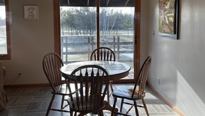 A dining area with a round table and four chairs, a ceiling light fixture, a framed artwork on the wall, and a view through a glass door to an outdoor area. - Large Private Condo on the Golf Course close to Many Lakes! (Cass Lake)
