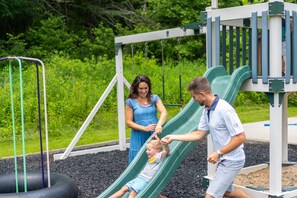 A playground with a green slide and a swing set.