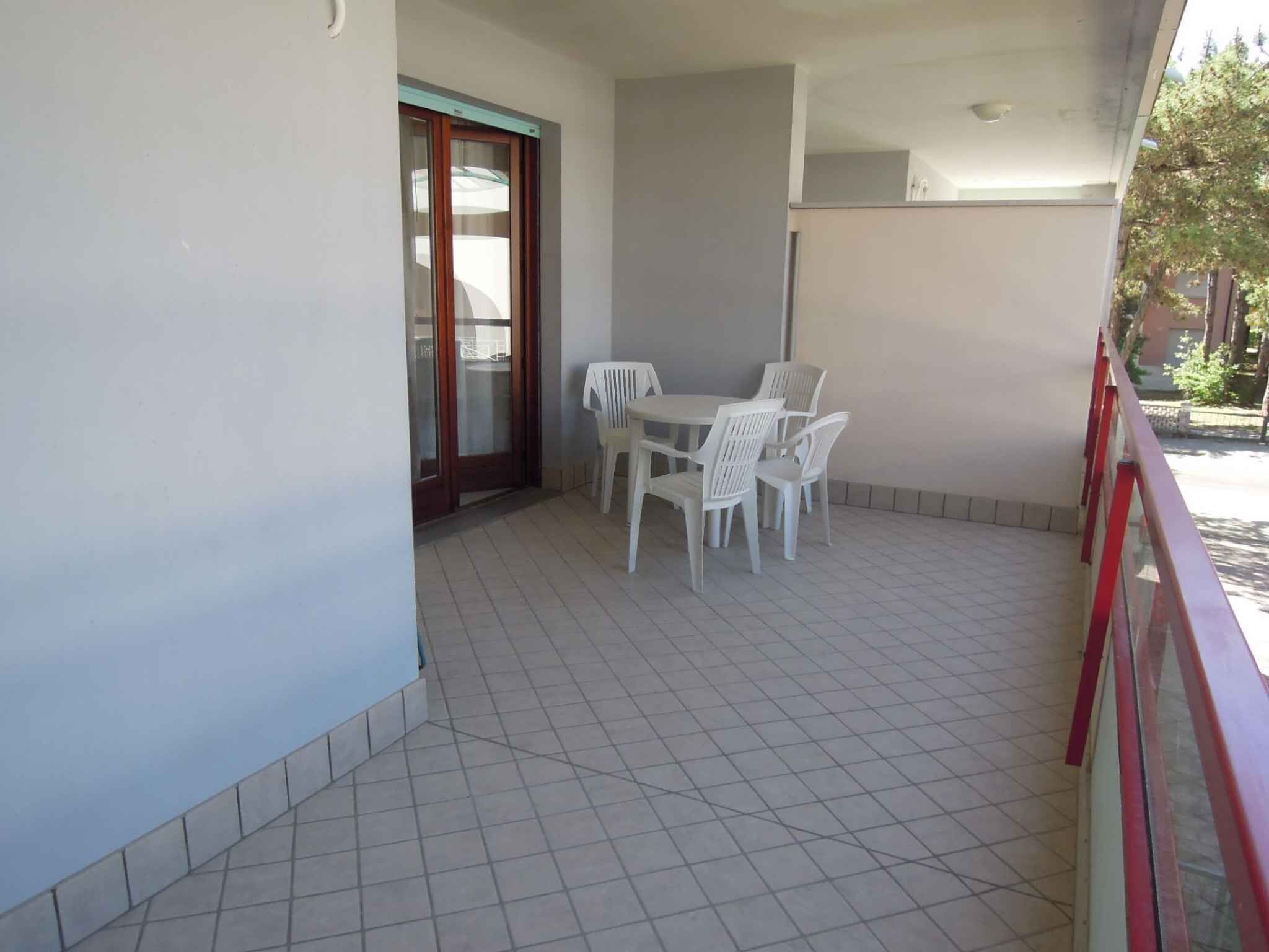 A balcony with a tiled floor, a table with chairs, and a sliding glass door.