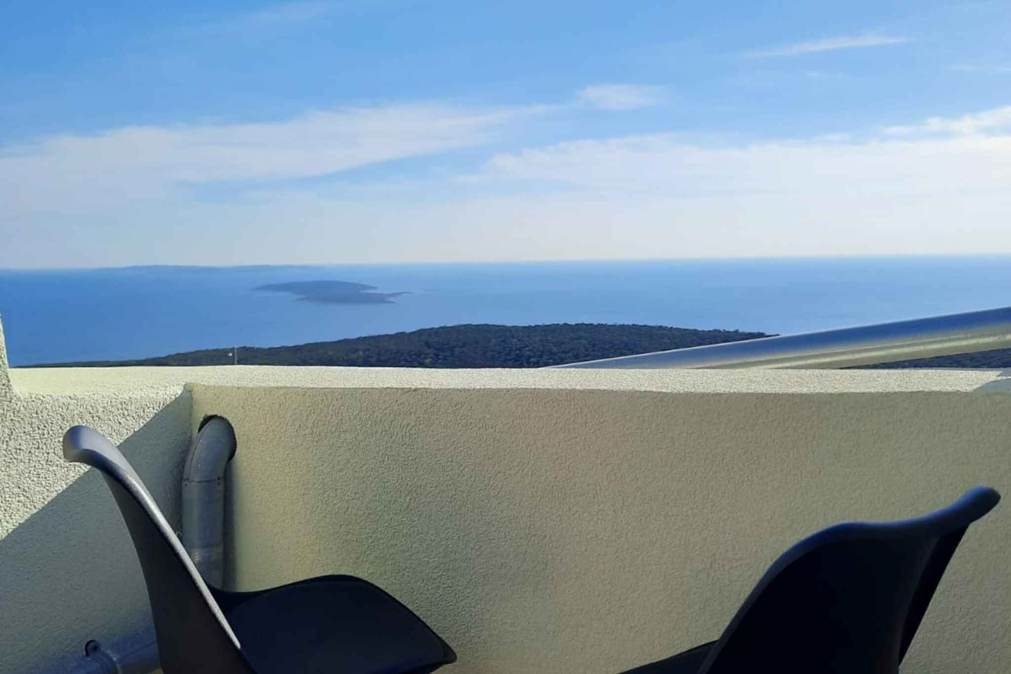 Een balkon met uitzicht op zee en een eiland in de verte.
