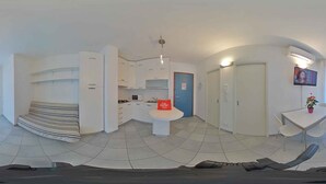 Ein modernes, kompaktes Wohnzimmer mit einer Küchenzeile, einem Essbereich und einer kleinen Sitzecke.