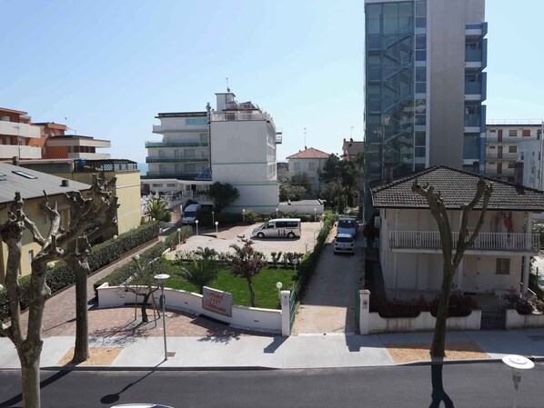 A hotel with a parking area, a sign indicating 'Hotel Vittoria', and a view of the surrounding buildings.
