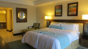 Une chambre d’hôtel avec un grand lit, une chaise, une table de chevet et une lampe fixée au mur.