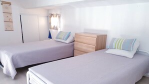 Un dormitorio con dos camas individuales, un aparador de madera y un armario.