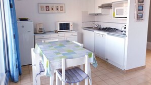 Una cocina compacta con una mesa de comedor, un microondas, una cafetera y un refrigerador.