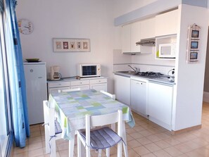 Eine kleine Küche mit Esstisch, Mikrowelle, Kaffeemaschine und Kühlschrank.