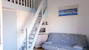Una habitación con una escalera, un sofá, un armario y un cuadro en la pared.