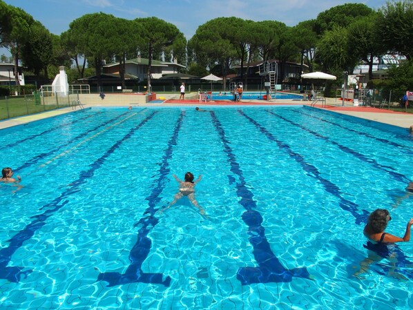A swimming pool with clear blue water, surrounded by trees and buildings.