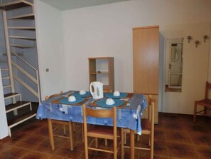 Un comedor con una mesa dispuesta para cuatro, una cafetera y un armario de madera.