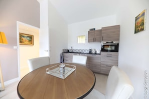 A modern kitchen with wooden cabinets, a built-in oven, and a window with blinds.