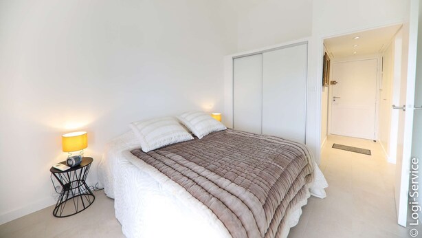 A bedroom with a bed, two bedside lamps, a nightstand, and a door to a hallway. - Near beach, Apartment 2 rooms air-conditioned (PORT GRIMAUD)