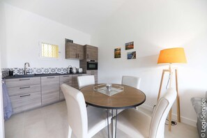A modern kitchen with white cabinets, a round dining table, and a lamp. - Near beach, Apartment 2 rooms air-conditioned (PORT GRIMAUD)