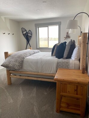Cozy bedroom with a large window, wooden bed, and bedside table.