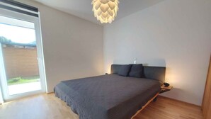 A bedroom with a large bed, a ceiling light fixture, and a sliding glass door leading to an outdoor area. - Holiday apartment new and cozy (Öblarn)