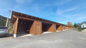 A row of single-story parking garages with open sides and a clear sky. - Holiday apartment new and cozy (Öblarn)