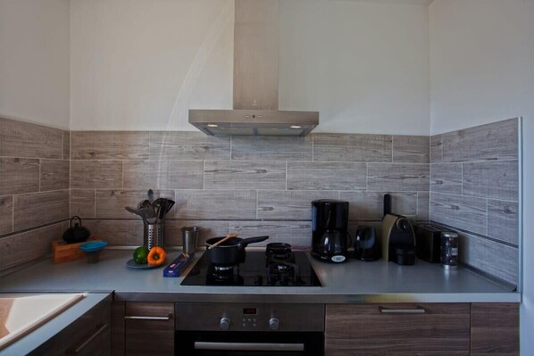 A modern kitchen with a stainless steel stove, a coffee maker, and a kettle on the countertop. - Casa Bianca (L'Île-Rousse)