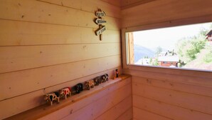 A wooden cabin interior with a window view, a shelf with cow figurines, and a directional sign. - Outside: Detached chalet on 3 floors with magnificent views, for 4 people - approx. 80m2Inside: Brig (St-Luc)