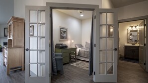 A bedroom with a desk, chair, and bed. There is a door leading to another room with a mirror and lights. - Perfect Golf Getaway near Glacier, 2/2 townhome right on golf course (Kalispell)