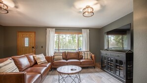A living room with a brown leather sofa, a round coffee table, and a cabinet with glass doors.