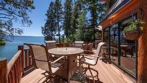 Eine Holzterrasse mit Gartenmöbeln mit Blick auf einen See.