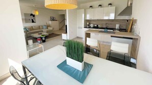 Een moderne keuken met witte kasten, een houten aanrecht en een hangende lamp.