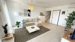 Een moderne woonkamer met een bank, salontafel en een trap naar een andere kamer.