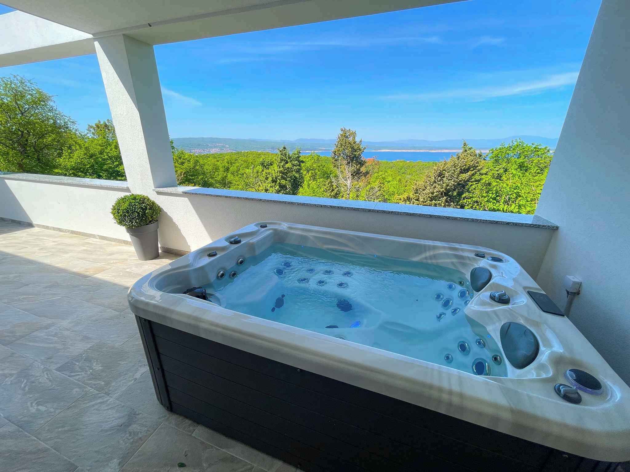 Ein Whirlpool auf einem Balkon mit freiem Blick auf das Meer und die grüne Landschaft.