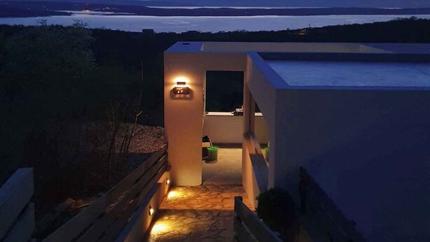 A modern building with a stone pathway leading to a lit entrance, overlooking a body of water and distant mountains. - Villa with great views and jacuzzi (Crikvenica)