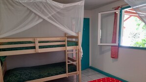 A bunk bed with a canopy, a window with a view of greenery, and a red patterned bedspread. - Gîte Ixora 4/6 pers in the residence Les Jardins de Pointe Noire, swimming pool (pointe noire)