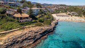 Une ville côtière avec un littoral rocheux, une plage de sable et des immeubles d’habitation.