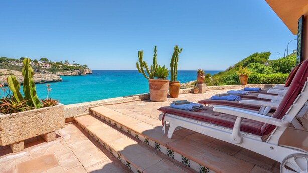Une terrasse avec des sièges extérieurs, une vue sur la mer et des plantes en pot.